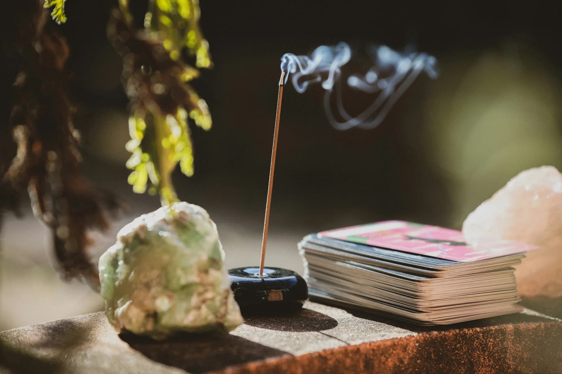 An incense stick burning beside pale stones in warm light